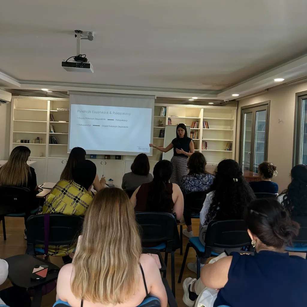 Klinik Psikolog Nihal Altıner'in psikoloji stajyerlerine yönelik verdiği Travma Sonrası Stres Bozukluğu (TSSB) ve psikolojik dayanıklılık eğitiminde sunum yaparken çekilmiş fotoğrafı.